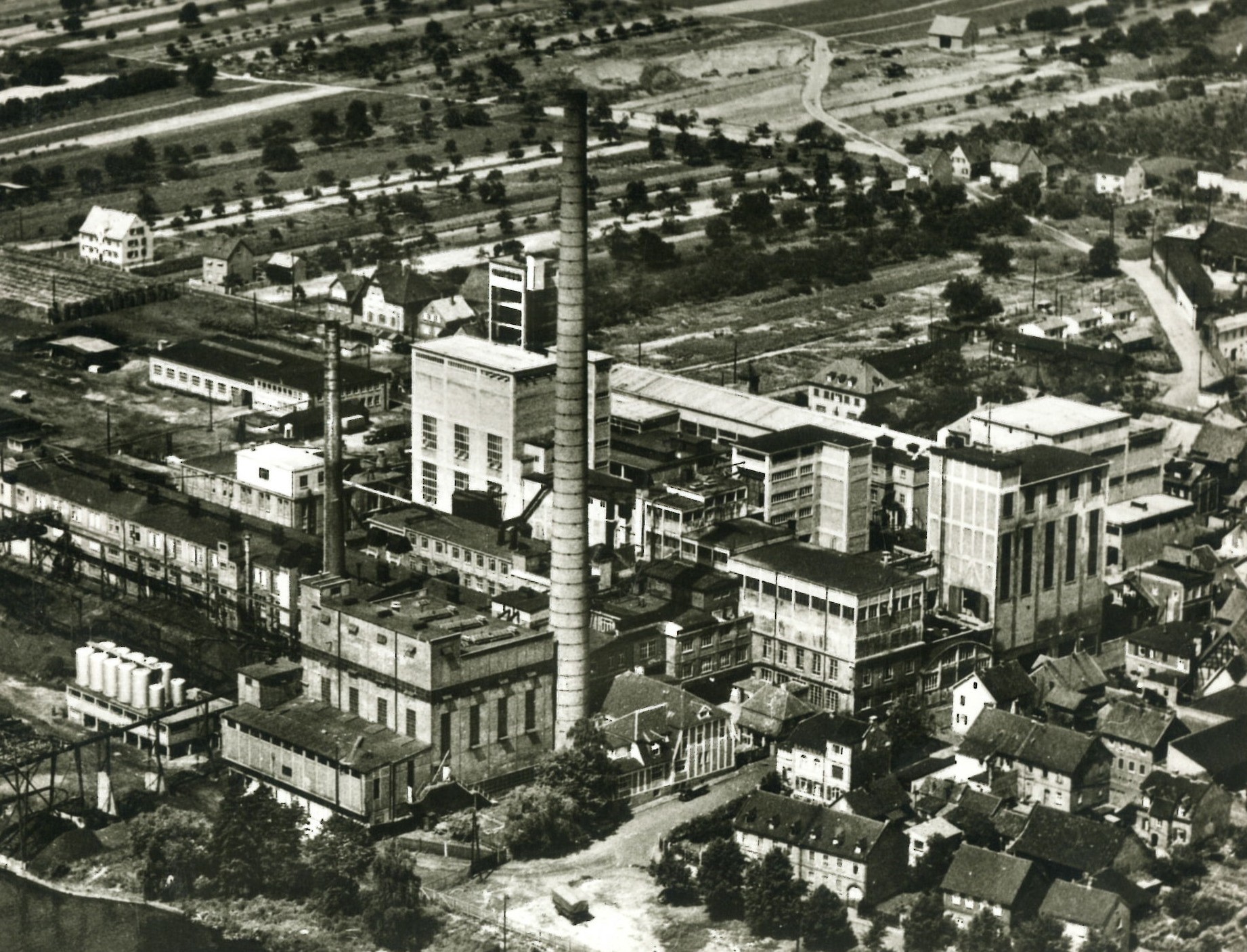 Die Schwar-Weiß-Fotografie zeigt das weitläufige Fabrikareal aus der Vogelperspektive.