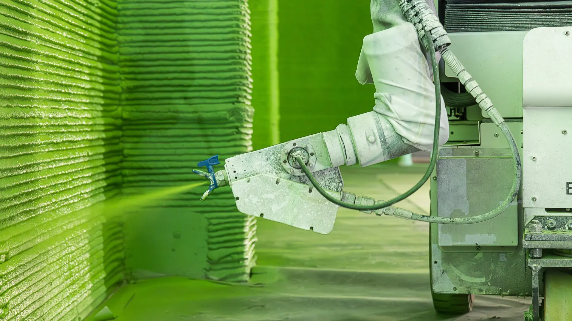 Roboterarm, der grüne Farbe an eine Wand sprüht.