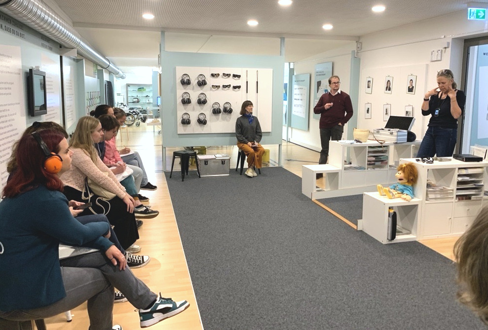 Eine Gruppe von Personen besucht die Ausstellung Hallo Freiheit: Zusammen über Barrieren der Frankfurter Stiftung für Gehörlose und Schwerhörige